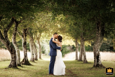 Elegant Saintes Wedding: Couple Poses Gracefully Amidst Double Rows Of Majestic Trees Romantic Saintes wedding photo of a couple posing elegantly between two beautiful rows of trees.