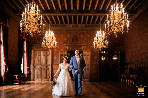 Newlywed Couple Shine Beneath Grand Chandeliers At La Rochelle City Hall Wedding Elegant portrait of a newlywed couple posing in a room with large chandeliers at La Rochelle City Hall.