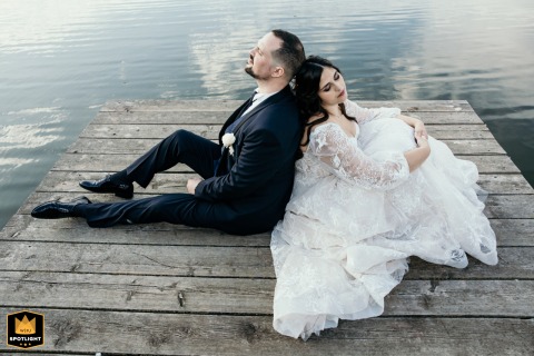 Bride And Groom Relax Lakeside On Wooden Dock In Bellaria Public Gardens, Italy Bride and groom relax on a wooden dock by the lake in Bellaria Public Gardens, Italy.