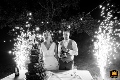 Couple Celebrates Love Amid Fireworks At Château de Millery-Autun Cake Table Black and white image: couple by cake table with fireworks igniting on each side at Château de Millery-Autun.