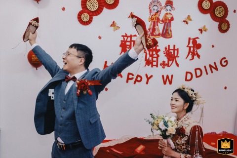 A Groom's Joyful Celebration: The Found Wedding Shoe Game A joyful groom in Kaifeng, China, celebrates finding the bride's hidden shoe during a traditional wedding game.