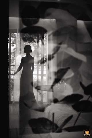 Francourt, France: A bride in silhouette reflected in a glass window after putting on her wedding dress.