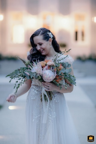 A Villa Monty Banks Evening: Bride's Softly Lit Portrait with Bouquet, Italy Villa Monty Banks, Cesena, Italy, provides the setting for a beautiful evening portrait of the bride holding her bouquet, softly lit by the venue's romantic lights.