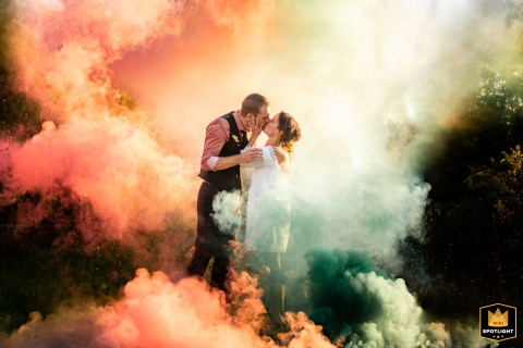 Newlyweds Share a Romantic Kiss Amidst the Colorful Smoky Scene At the Saint Félix de Lauragais, the newlyweds kiss amongst a colorful smoky scene.