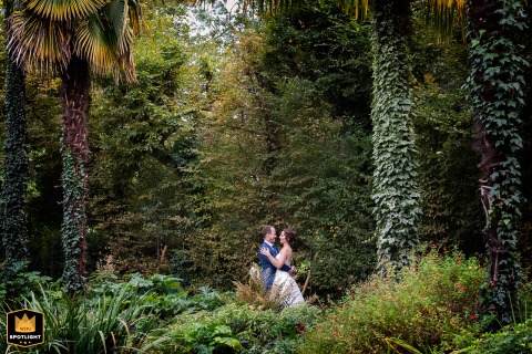 Tender Embrace and Intimate Kiss Surrounded by Lush Toulouse Park Greenery In a park in Toulouse, Haute-Garonne, the newlyweds share a tender moment, embracing and kissing intimately while surrounded by the venue's lush green vegetation.