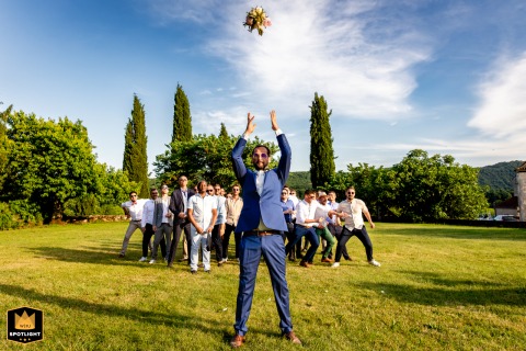 Groom Playfully Tossing Bride's Bouquet High In Air At French Estate At an estate in Tarn-et-Garonne, the groom is playfully tossing the bride's bouquet high into the air, creating a humorous and inverted twist on a traditional moment during the wedding celebration.