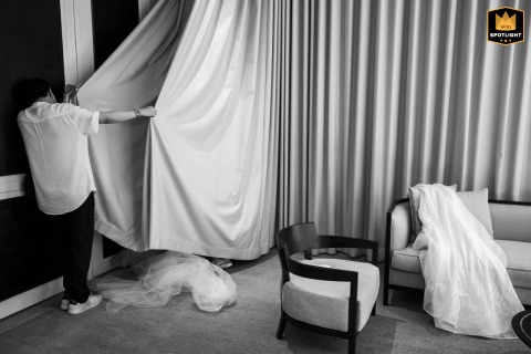 Bride hidden behind curtains at Four Seasons Bangkok, capturing a quiet moment as time ticks away before the wedding.