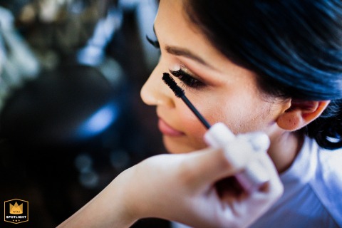 At a residence in Livermore, California, a close-up detail shot captures someone carefully applying mascara to the bride's eye during her preparation.