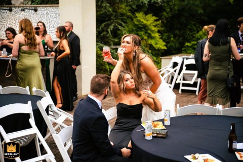 In Claymont, Delaware, a friend quickly delivers an item to the bride with perfect timing, responding to her subtle, nonverbal signal for food.