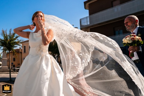 In Udine, Italy, the bride arrives at the ceremony as her long veil dramatically lifts and billows, gently kissed by the wind.