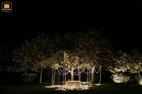 In the courtyard of Podere Palazzo, Cesena, Italy, tree lights softly illuminate an intimate wedding table at night. Two glasses rest side by side, setting a romantic and tranquil end-of-day scene.