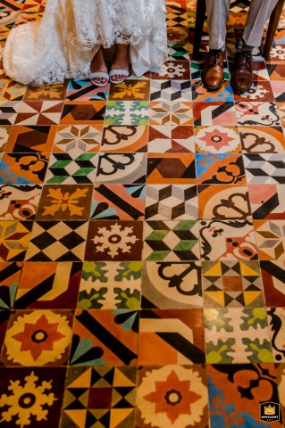 A close-up shot highlights the newlyweds’ feet together on colorful Mexican floor tiles in Playa del Carmen, showcasing their footwear against intricate, vibrant patterns for a charming cultural detail. 