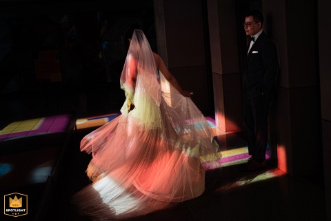 At Top of the Rock in New York City, the bride’s dress shimmers as it catches rainbow prism lighting in the hallway, transforming the space into a vibrant, theatrical setting for an unforgettable wedding portrait. 