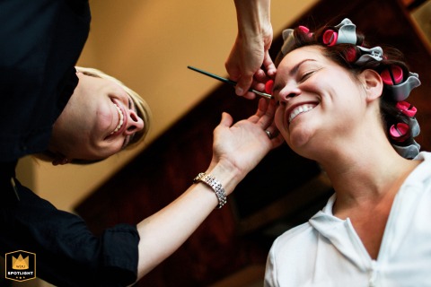 At Oceano Hotel and Spa in Half Moon Bay, California, a low-angle shot captures the bride with curlers in her hair as she has her makeup applied, highlighting the focused preparations and relaxed atmosphere before the wedding ceremony.