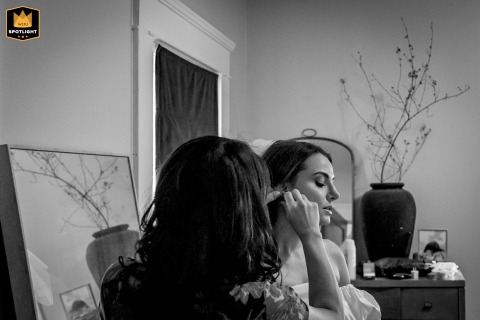 Inside a private home in Ventura, California, the bride’s sister gently fastens their grandmother’s cherished earrings onto the bride, captured in a black and white image that conveys familial love, tradition, and quiet anticipation before the ceremony.