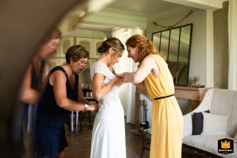 At Château de Launac in Haute-Garonne, the bride is captured during her preparations, her reflection beautifully framed in a beveled-edge mirror that artfully echoes its shape, highlighting her focused expression in the elegant setting.