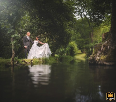 Couple Enjoys A Riverside Portrait Along The Caudeau River In Dordogne, France Along Caudeau River in Liorac/Louyre, Dordogne, a couple enjoys a photo session by the riverside, surrounded by lush greenery and calm water.