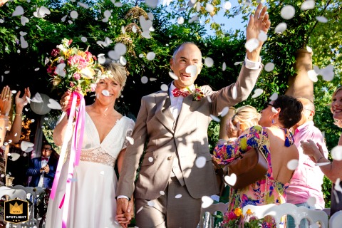   At Parc Coulassy in Nègrepelisse, France, the couple exits their secular ceremony beneath a cascade of flower petals, marking the start of their celebration surrounded by nature.