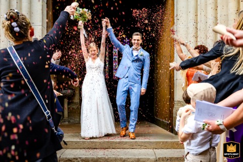   Outside Saint Antonin Noble Val church in Tarn-et-Garonne, France, newlyweds emerge through a joyful flurry of dried flower petals, welcomed by friends and family.