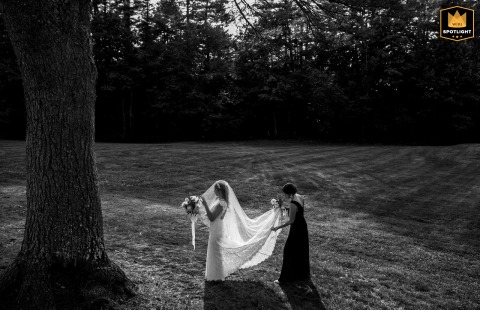   At Sebago Lake, Maine, a bridesmaid helps the bride adjust her veil in beautiful, natural light just before the ceremony, ensuring everything is perfect for the walk down the aisle.