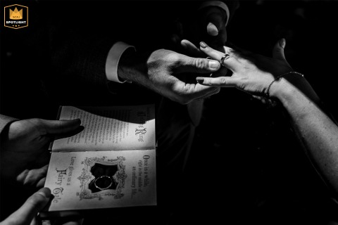   A bw close-up photo at a ceremony in Zuid Holland highlights the intricate details of hands as rings are exchanged, signifying the couple’s bond and promises.