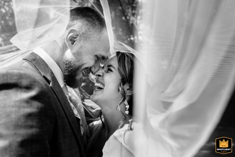   In the garden of their wedding location in Zuid Holland, the bridal couple shares laughter, noses touching as they embrace a session of genuine happiness together.