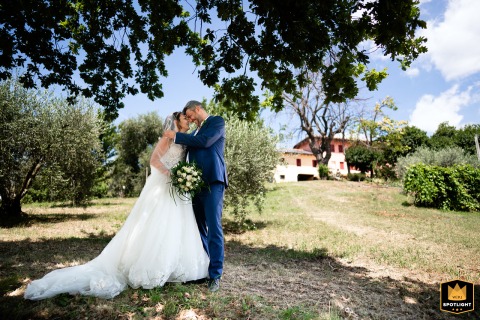   A timeless portrait of the newlyweds is taken under a large tree at a private residence in Conegliano, Italy, capturing their loving expressions as they celebrate their new life together.