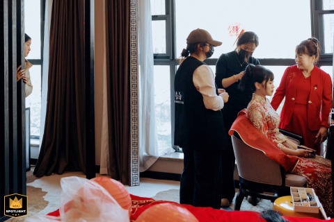 Mother Observes Bridal Makeup As A Flower Girl Peeks In Kaifeng, China A mother looks on while her daughter, the bride, has makeup applied in Kaifeng, China, as a flower girl peeks curiously from behind, sharing in the excitement of wedding preparations.