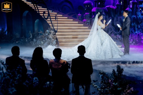   In Kaifeng, China, the parents of the bride and groom sit together below the stage, attentively watching the newlyweds as they recite their marriage vows.