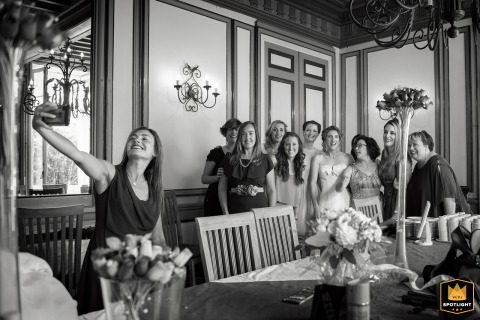   At Château Le Haget in Gers, a bridesmaid gathers with the bride, maid of honor, and witnesses, snapping a cheerful group photo with her phone to remember the occasion.