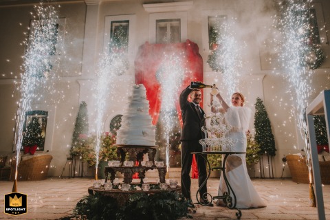 The wedding cake cutting at Casa Freda in Foggia transforms into a theatrical spectacle, framed by symmetrical architecture and erupting lights, elevating the ritual to a dramatic visual high point.