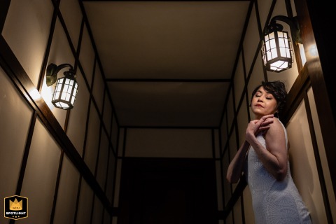 In a quiet scene at her home in Orleans, MA, the bride stands alone under warm light, pausing thoughtfully before stepping into the ceremony that awaits her.