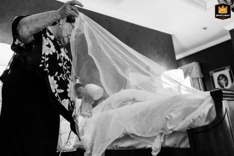 A caring hand lifts and arranges a bridal veil at Daniel Webster Inn in Sandwich, MA, beautifully blending traditional rituals with gentle, supportive attention in preparation.