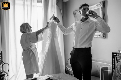 Relaxed Family Moment At Lake Como Italy Features A Brother Assisting His Mother Before The Ceremony During preparations at Lake Como, Italy, the bride’s brother assists their mother with her dress while enjoying a beer, illustrating a relaxed and supportive family moment before the ceremony.