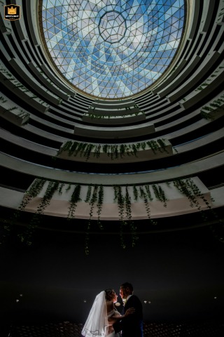 A young couple in Cancun stands together under a vast dome sky, their connection and wonder set against the breathtaking panorama of this romantic destination.