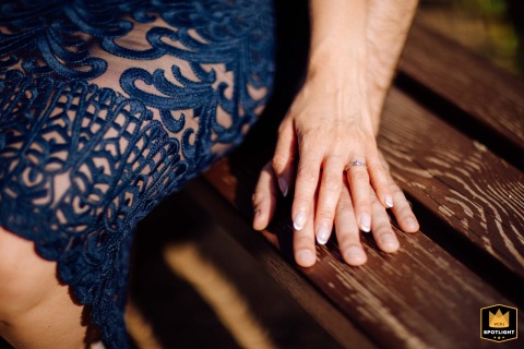 Hands rest on a wooden bench at Hotel Park in Budapest, Hungary, with sunlight accentuating the jewelry in a subtle, meaningful display.