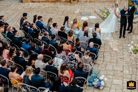 At Masseria Salamina in Puglia, Italy, the bride and groom share a meaningful look with their guests during their ceremony, surrounded by the beauty of the Italian countryside.