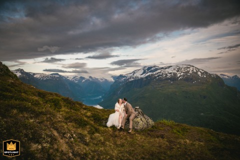 In Loen, Norway, the couple shares a tender kiss with dramatic views of the fjord as their backdrop, enveloped by the stunning natural scenery.
