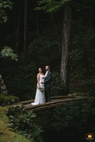 On a scenic bridge in the forests of Kyoto, Japan, the couple stands side by side, displaying a deep connection with nature enveloping them in a tranquil atmosphere.
