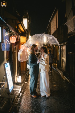 In the lively streets of Kyoto, Japan, the couple poses together at night, surrounded by city lights and the energy of passersby during their destination celebration.