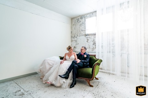 At The Saint Vrain in Longmont, Colorado, the couple is elegantly posed together on a green couch in a bright, white room, creating a modern and sophisticated portrait.