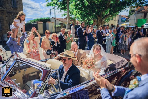 Newlyweds Make A Grand Entrance In A Convertible Outside Chateau De Montrouge In Loire The couple is greeted by cheers and sunlight outside Château de Montrouge in Loire, their convertible car grand entrance filled with radiant emotion and joyful anticipation.