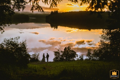The couple shares an intimate sunset embrace at Lake Saint Pardoux in Limousin, their silhouettes framed against the tranquil lakeside.