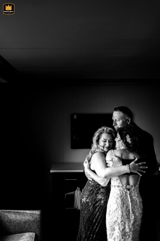 In a heartfelt embrace at Merion Tribute House, Philadelphia, a bride lovingly holds her parents close, honoring the two hearts that have always supported her.