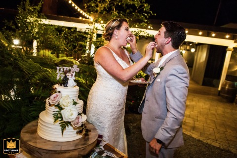 Newlyweds Feed Each Other Cake Under The Stars At Deer Park Villa In Fairfax California The couple feeds each other a slice of cake outdoors at night at Deer Park Villa in Fairfax, CA, joyfully sharing a sweet moment during their reception under the stars.