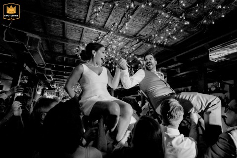 Friends Lift The Bride And Groom For The Spirited Hora Dance In Ventura California At Cafe Fiore in Ventura, CA, the bride and groom are lifted excitedly into the air by friends during the spirited Hora dance, filling the Italian restaurant with laughter and celebration.