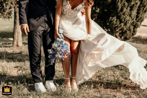 Windswept fabric billows around the bride with her groom at Castello di Ribano, Savignano, Italy, as delicate details of her gown flow against the rustic landscape.