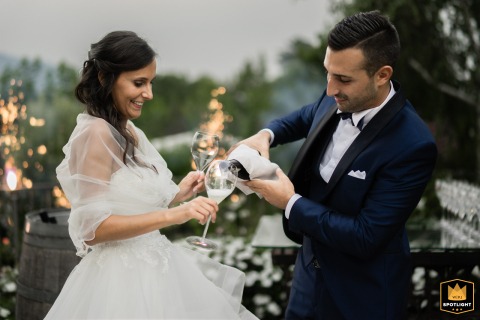 At Relais Franciacorta in Colombaro, Lombardy, the groom pours sparkling wine into the bride’s glass, celebrating together with a picturesque view of the Italian countryside.