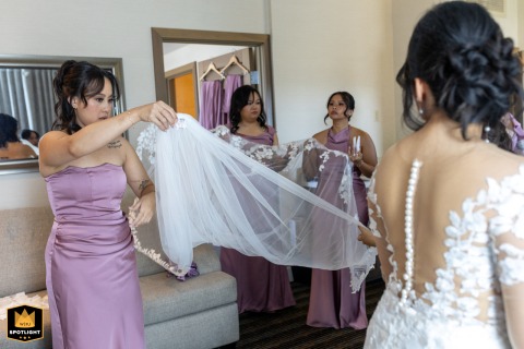 Bridesmaids gather in Los Angeles, California, working together to arrange and manage the bride’s exceptionally long veil as excitement for the day builds.