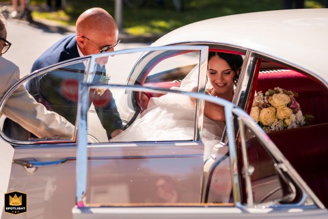 Excitement marks the arrival in Udine, Italy, as the bride steps out of the antique car, ready to walk into the ceremonial venue with anticipation in her expression.